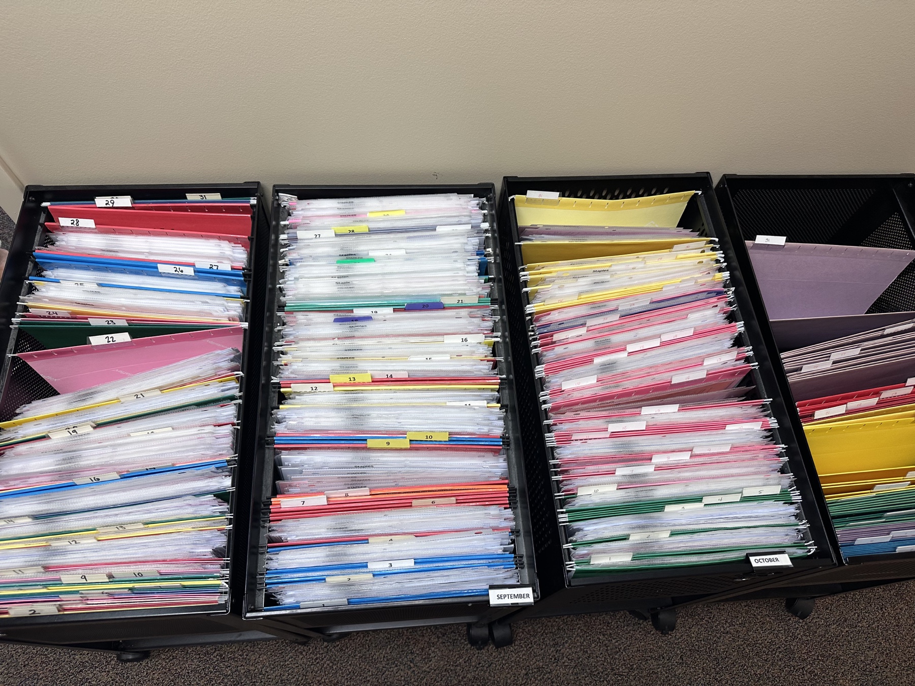 Rows of color-coded physical folders arranged by procedure date at an ambulatory surgery center
